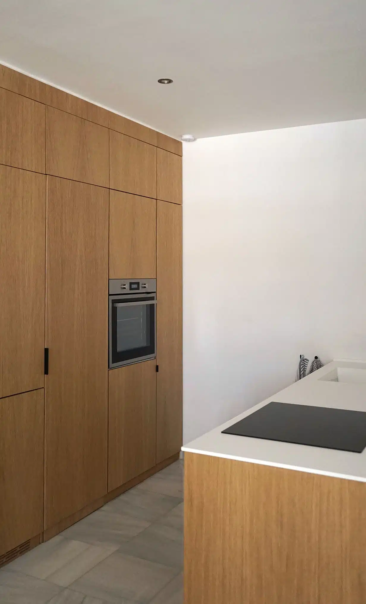 Cocina minimalista de IKEA revestida con paneles CUBRO con acabado en madera de roble natural. Horno y un frigorífico integrado.